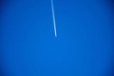 Low angle view of vapor trail against clear blue sky