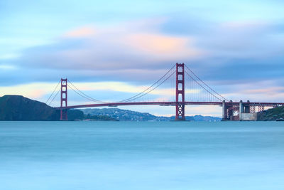 Suspension bridge over sea against sky