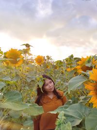 Portrait of woman with arms raised standing against yellow sky