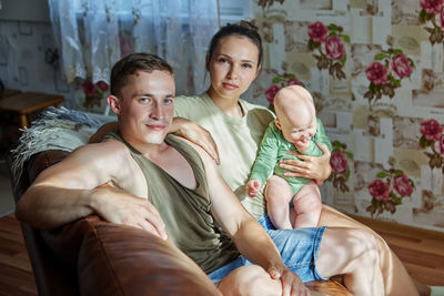 Portrait of happy friends sitting on bed at home
