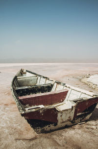 Abandoned boat at beach against sky