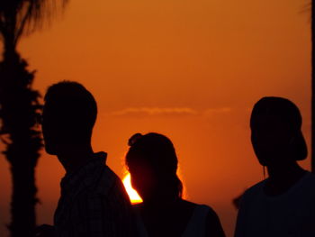 Silhouette people against orange sky during sunset