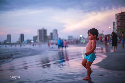 Full length of shirtless man in city against sky during sunset