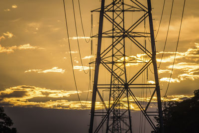 Low angle view of silhouette electricity pylon against sky