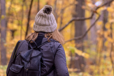 Rear view of woman standing by tree during autumn