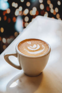 Close up selective focus coffee cup with latte art on dark background with bokeh.