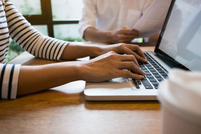 Close-up of man using laptop on table