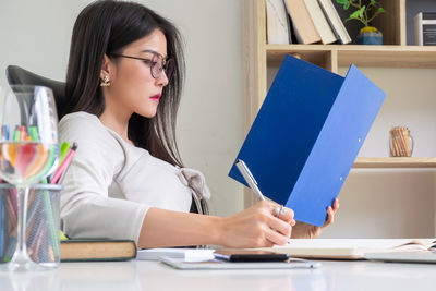 Young woman looking away while sitting on table