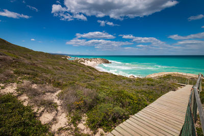 Wooden walkway leading to indian ocean beach, de hoop nature reserve, south africa against sky