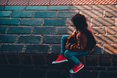 Full length of woman sitting against wall