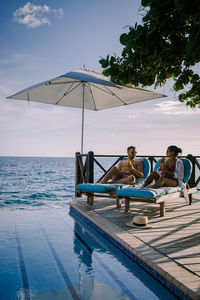 People sitting near pool against sky