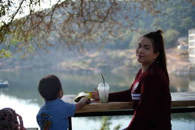 Portrait of woman with son sitting at table against sky