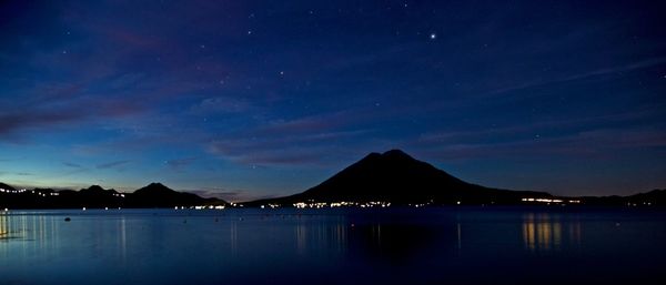 Scenic view of illuminated sea against sky at night