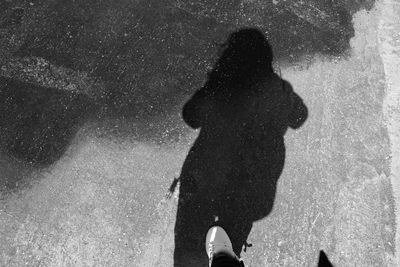 Low section of silhouette woman standing on puddle