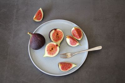 Round plate with sliced figs, small fork, whole fig and pieces, fruit with lots of small seeds