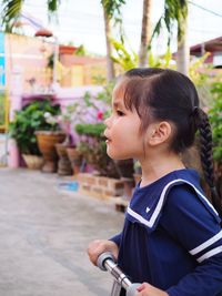 Side view of girl looking away while standing by push scooter