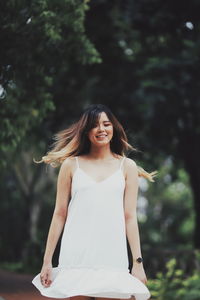 Smiling young woman against blurred trees
