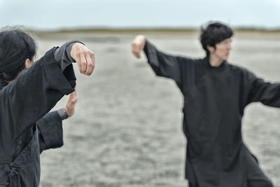 Rear view of men standing at beach