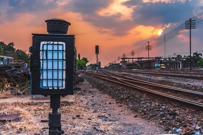 Railroad track amidst field against sky during sunset