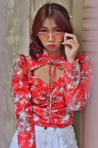 Midsection of woman holding red while standing against wall