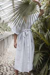 Woman standing by plants in greenhouse