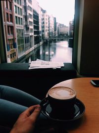 Cropped hand holding coffee on table at home