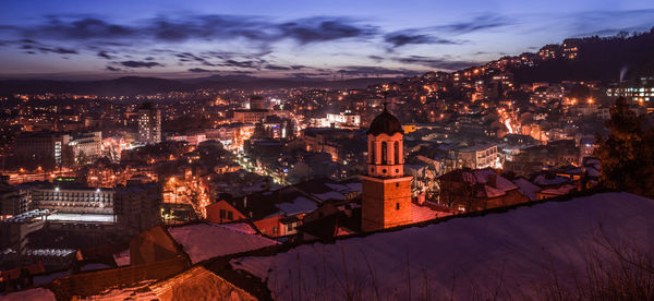 Illuminated cityscape against sky at dusk