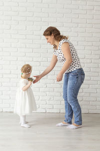 Full length of woman standing against wall