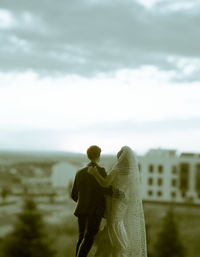 Rear view of couple figurine on land against sky