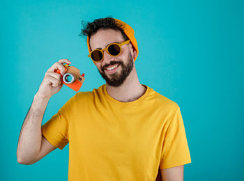 Young man wearing sunglasses standing against blue background