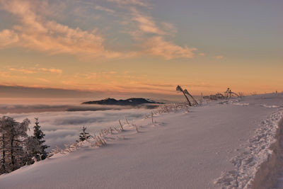 Scenic view of snow covered land against sky during sunset