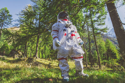 Full length of man standing amidst trees in forest