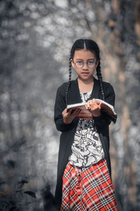 Portrait of young woman using phone while standing outdoors