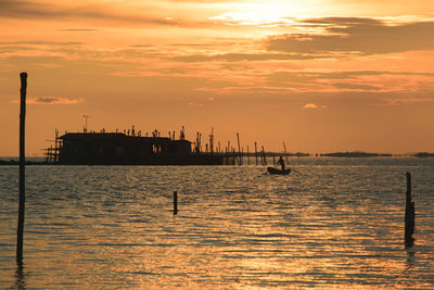 Silhouette boats in sea against sky during sunset