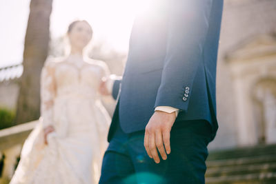 Midsection of bride and bridegroom holding hands