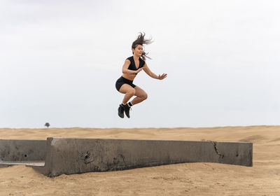 Full length of woman jumping on land against sky
