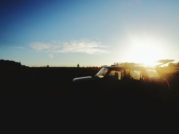 Silhouette car on field against sky during sunset