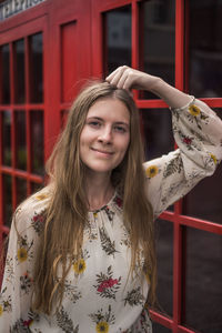 Portrait of young woman standing against building