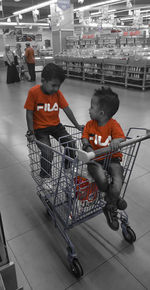 Boy sitting in shopping cart in store