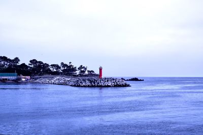 Lighthouse by sea against sky