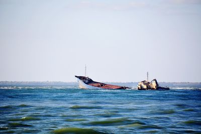 Boat sailing in sea against clear sky