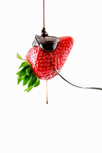 High angle view of red berries on white background