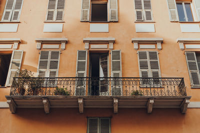 Low angle view of a traditional colourful apartment block building with a balcony in nice, france.