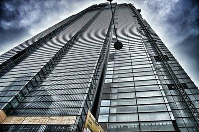 Low angle view of modern building against cloudy sky