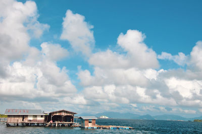 Buildings by sea against sky