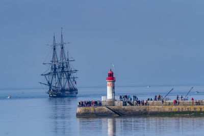 Lighthouse by sea against sky