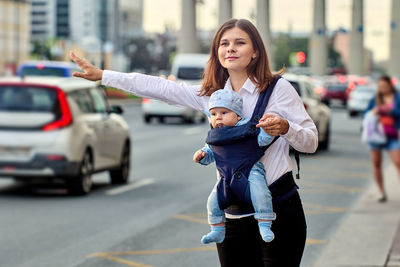 Portrait of smiling young woman standing on street in city