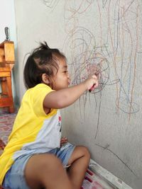 Side view of cute girl against wall