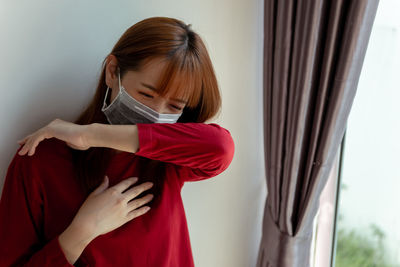 Woman standing by window at home