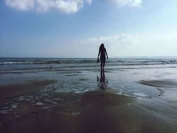 Woman standing on beach against sky